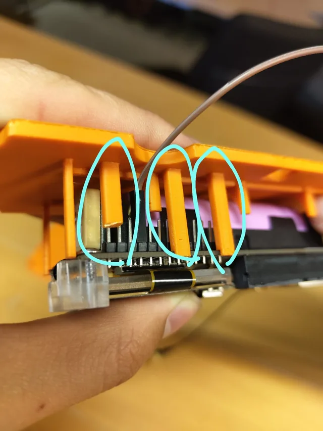 The T-Beam's header pins beside the case's orange side-button plungers, with the instrument maker's drawn marks where the fit still needs work.